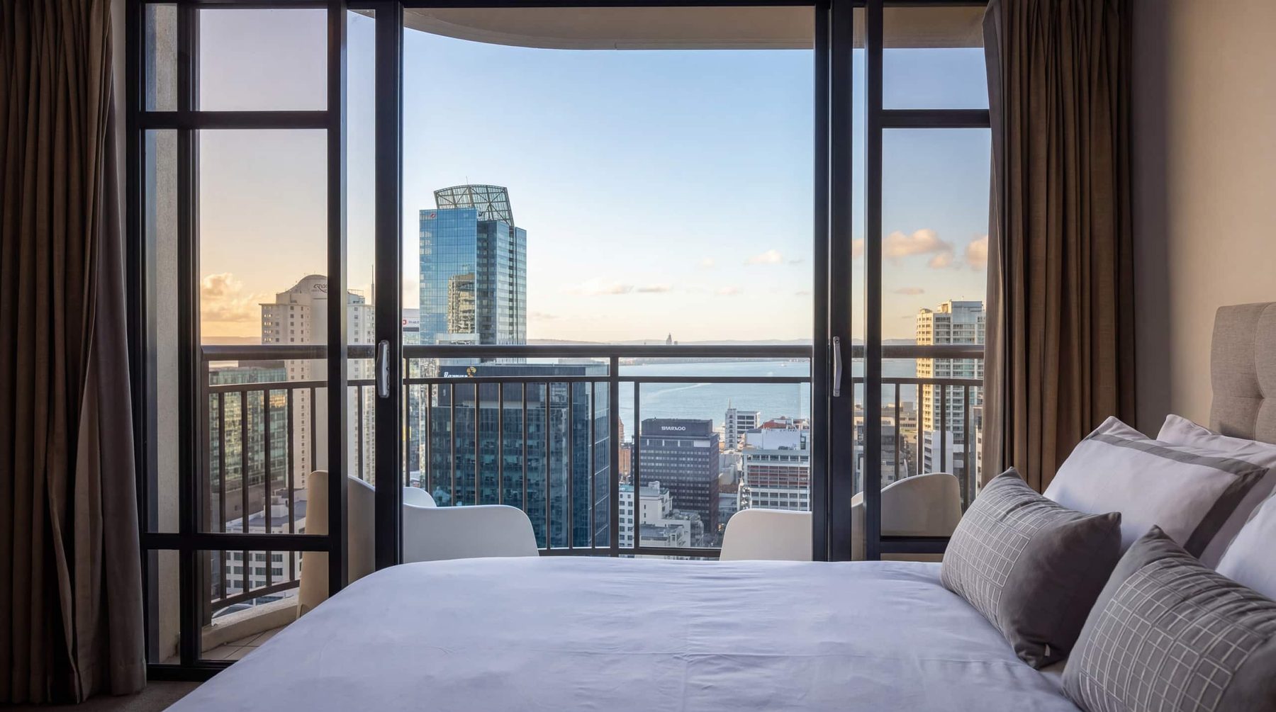 Bedroom of a Dash BnB managed apartment with balcony views over the Auckland CBD skyline and harbour